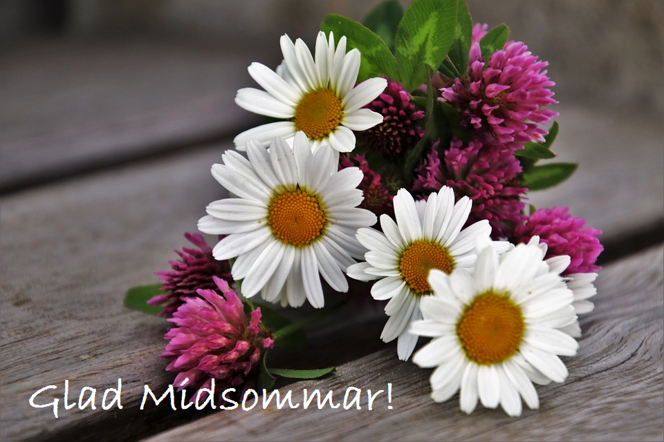 En bukett blommor med prästkragar och klöverblommor ligger på ett träbord.